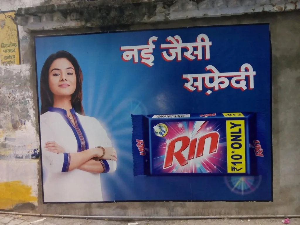 Digital wall paintings on a public wall in India, showcasing a colorful advertisement with bold graphics and Hindi text, used for outdoor brand promotion.
