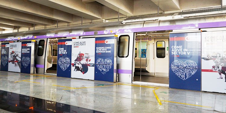 Bandhan Bank metro ad campaign at Salt Lake Sector V station by Acme Advertising Co. in Kolkata, using full train and platform branding.